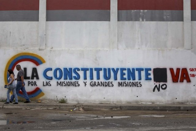 ACOMPAÑA CRÓNICA: VENEZUELA CRISIS - CAR007. CARACAS (VENEZUELA), 15/07/2017.- Un pareja camina frente a una pared con propaganda de la Asamblea Nacional Constituyente hoy, sábado 15 de julio de 2017, en Caracas (Venezuela). Con el éxito asegurado en las zonas privilegiadas de Caracas, donde el chavismo nunca tuvo predicamento, la consulta opositora sobre la Asamblea Constituyente que impulsa el presidente Nicolás Maduro se la juega ahora en los barrios populares que vieron en Hugo Chávez el mesías de la Revolución Bolivariana. EFE/Miguel Gutiérrez