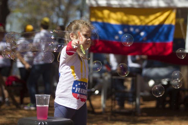 BRA111. BRASILIA (BRASIL), 16/07/2017.- Una niña juega en la calle junto a las mesas donde la comunidad venezolana de Brasilia vota la consulta popular impulsada por los opositores del presidente Nicolás Maduro ante la negativa del Ayuntamiento a que se realizase en un centro cívico por la falta de permisos hoy, domingo 16 de julio de 2017, en Brasilia (Brasil). La oposición venezolana lanza este domingo su mayor desafío al Gobierno del presidente Nicolás Maduro con la convocatoria de una consulta calificada de ilegal desde el oficialismo en la que espera que el pueblo se pronuncie masivamente contra el proceso constituyente impulsado por el chavismo. EFE/Joédson Alves