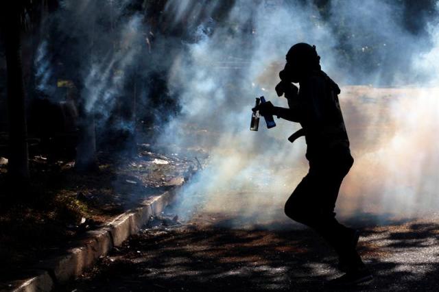 Un manifestante corre entre el gas lacrimógeno hoy, miércoles 26 de julio de 2017, durante una manifestación en Barquisimeto (Venezuela). La oposición venezolana cifró hoy en un 92 % en su primera jornada el seguimiento del paro general de 48 horas convocado para el miércoles y el jueves para exigir al presidente, Nicolás Maduro, que retire la elección este 30 de julio de una Asamblea Constituyente para redactar una nueva Carta Magna. EFE/PASQUALE GIORGIO