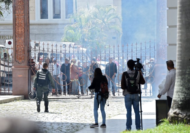 Supporters of Venezuelan President Nicolas Maduro stand at the gate of the National Assembly building in Caracas before storming it on July 5, 2017 as opposition deputies hold a special session on Independence Day. A political and economic crisis in the oil-producing country has spawned often violent demonstrations by protesters demanding President Nicolas Maduro's resignation and new elections. The unrest has left 91 people dead since April 1. / AFP PHOTO / Juan BARRETO