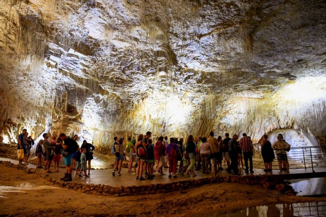 People visit the natural cave of Choranche, in the Vercors region near Grenoble, on August 3, 2017. Since the beginning of the heat wave, there has been an increase of at least 10 percent in the number of cave visitors, looking for beautiful natural sites, but also for underground freshness with temperatures around 15 Degrees Celsius. / AFP PHOTO / JEAN-PIERRE CLATOT