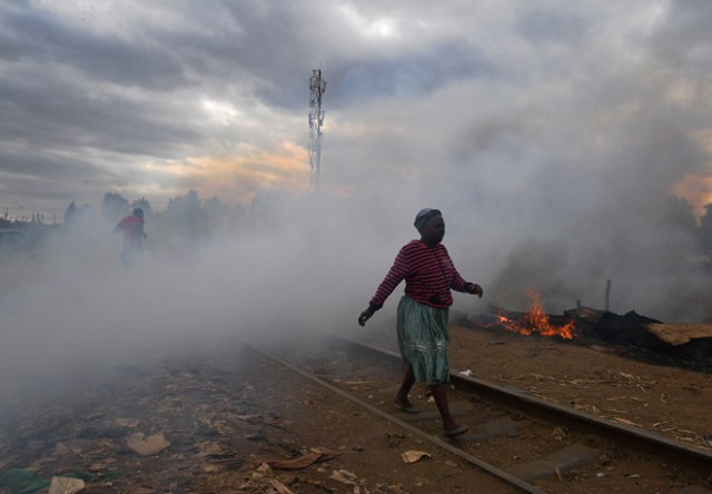 A woman walks past a shack which was burnt to the ground by protestors in the Kibera slum in Nairobi on August 12, 2017. Three people, including a child, have been shot dead in Kenya during opposition protests which flared for a second day Saturday after the hotly disputed election victory of President Uhuru Kenyatta. Demonstrations and running battles with police broke out in isolated parts of Nairobi slums after anger in opposition strongholds against August 8 election that losing candidate Raila Odinga claims was massively rigged. / AFP PHOTO / CARL DE SOUZA