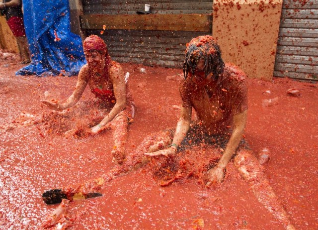 Revellers covered in tomato pulp take part in the annual "Tomatina" festival in the eastern town of Bunol, on August 30, 2017. The iconic fiesta -- which celebrates its 72nd anniversary and is billed at "the world's biggest food fight" -- has become a major draw for foreigners, in particular from Britain, Japan and the United States. / AFP PHOTO / JAIME REINA