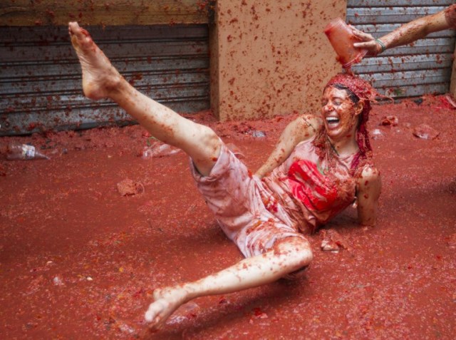 A reveller covered in tomato pulp takes part in the annual "Tomatina" festival in the eastern town of Bunol, on August 30, 2017. The iconic fiesta -- which celebrates its 72nd anniversary and is billed at "the world's biggest food fight" -- has become a major draw for foreigners, in particular from Britain, Japan and the United States. / AFP PHOTO / JAIME REINA