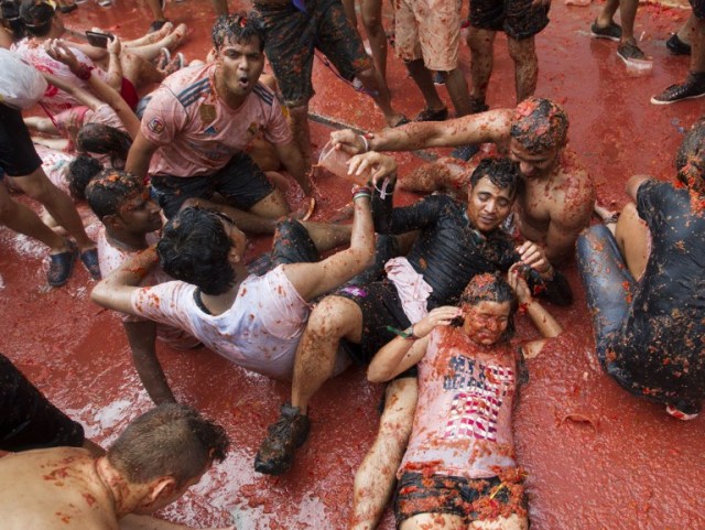 Revellers covered in tomato pulp take part in the annual "Tomatina" festival in the eastern town of Bunol, on August 30, 2017. The iconic fiesta -- which celebrates its 72nd anniversary and is billed at "the world's biggest food fight" -- has become a major draw for foreigners, in particular from Britain, Japan and the United States. / AFP PHOTO / JAIME REINA