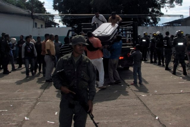 A soldier stands guard near to people downloading a coffin from a truck outside the Jose Gregorio Hernandez hospital in Puerto Ayacucho, Venezuela August 17, 2017. REUTERS/Jose Torres