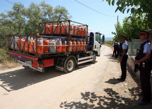 Un camión (i) retira parte de las 120 bombonas de butano halladas en el chalet de Alcanar Platja utilizado por los terroristas de Barcelona y Cambrils 