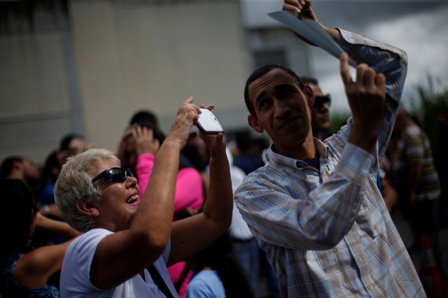 A man holds an X-ray as a woman takes a photograph of a partial solar eclipse at the Venezuelan Institute for Scientific Research (IVIC) in San Antonio de los Altos, Venezuela, August 21, 2017. REUTERS/Andres Martinez Casares