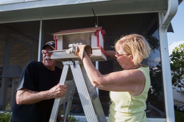 Don and Marie Larcom put a bird feeder in front of their house at the Enchanted Shores manufactured home park in Naples, Florida, on September 11, 2017 after Hurricane Irma hit Florida. / AFP PHOTO / NICHOLAS KAMM