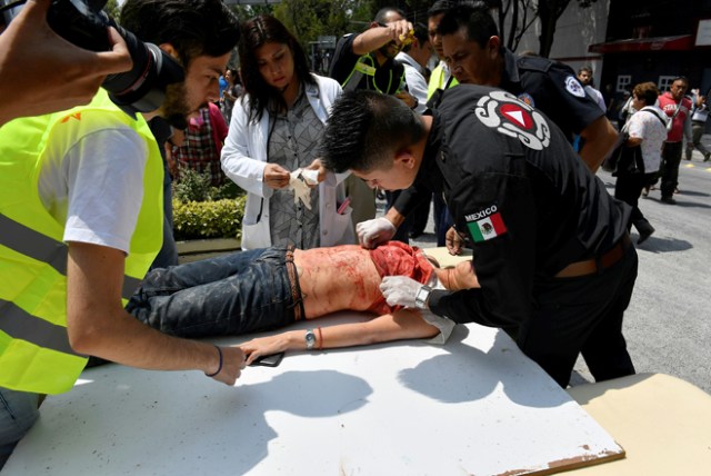 A woman is assisted after being injured during a quake in Mexico City on September 19, 2017. A powerful earthquake shook Mexico City on Tuesday, causing panic among the megalopolis' 20 million inhabitants on the 32nd anniversary of a devastating 1985 quake. The US Geological Survey put the quake's magnitude at 7.1 while Mexico's Seismological Institute said it measured 6.8 on its scale. The institute said the quake's epicenter was seven kilometers west of Chiautla de Tapia, in the neighboring state of Puebla. / AFP PHOTO / Omar TORRES