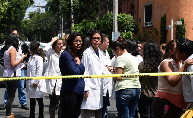 People remain in the streets after a powerful quake rattled Mexico City on September 19, 2017. A powerful earthquake shook Mexico City on Tuesday, causing panic among the megalopolis' 20 million inhabitants on the 32nd anniversary of a devastating 1985 quake. The US Geological Survey put the quake's magnitude at 7.1 while Mexico's Seismological Institute said it measured 6.8 on its scale. The institute said the quake's epicenter was seven kilometers west of Chiautla de Tapia, in the neighboring state of Puebla. / AFP PHOTO / Ronaldo SCHEMIDT