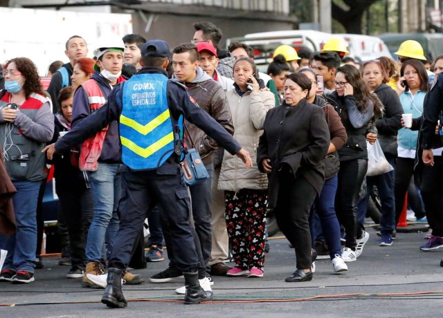 A police officer and people wait along the street after a tremor was felt in Mexico City, Mexico September 23, 2017. REUTERS/Henry Romero