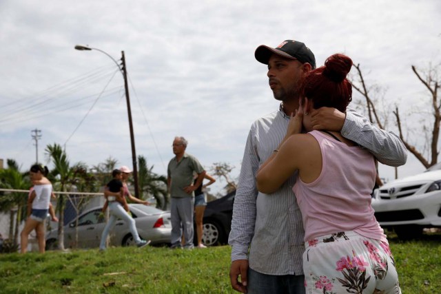 Local residents react while they look at the water flowing over the road at the dam of the Guajataca lake after the area was hit by Hurricane Maria in Guajataca, Puerto Rico September 23, 2017. REUTERS/Carlos Garcia Rawlins