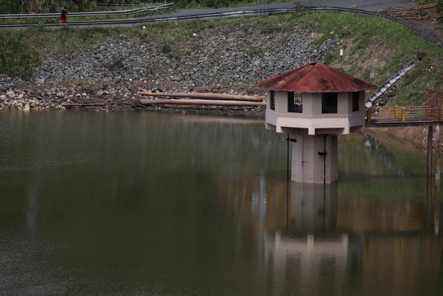 People walk next to a water level tower of the dam at the Guajataca lake after the area was hit by Hurricane Maria in Guajataca, Puerto Rico September 23, 2017. REUTERS/Carlos Garcia Rawlins