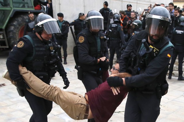 Spanish Guardia Civil guards drag a man outside a polling station in Sant Julia de Ramis, where Catalan president was supposed to vote, on October 1, 2017, on the day of a referendum on independence for Catalonia banned by Madrid. More than 5.3 million Catalans are called today to vote in a referendum on independence, surrounded by uncertainty over the intention of Spanish institutions to prevent this plebiscite banned by justice. / AFP PHOTO / Raymond ROIG