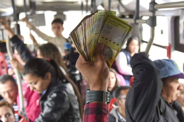 Venezuelan national Jhonger Pina, 25, sells candies and shows Bolivar bills as a curiosity to passengers, in exchange for local coins on a bus in Bogota, on October 26, 2017. Up to October 2017 there were 470,000 Venezuelans in Colombia, who left their country to escape the hardship and violence of its economic and political crisis. / AFP PHOTO / Raul Arboleda / TO GO WITH AFP STORY by Daniela QUINTERO and Santiago TORRADO