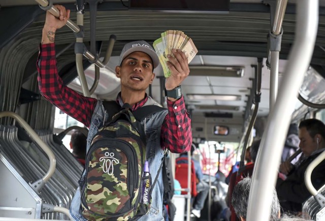 Venezuelan national Jhonger Pina, 25, sells candies and shows Bolivar bills as a curiosity to passengers, in exchange for local coins on a bus in Bogota, on October 26, 2017. Up to October 2017 there were 470,000 Venezuelans in Colombia, who left their country to escape the hardship and violence of its economic and political crisis. / AFP PHOTO / Raul Arboleda / TO GO WITH AFP STORY by Daniela QUINTERO and Santiago TORRADO