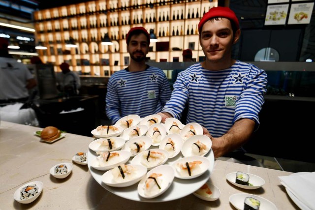 Fishmongers present fish dishes at a stand during a press tour at FICO Eataly World agri-food park in Bologna on November 9, 2017. FICO Eataly World, said to be the world's biggest agri-food park, will open to the public on November 15, 2017. The free entry park, widely described as the Disney World of Italian food, is ten hectares big and will enshrine all the Italian food biodiversity. / AFP PHOTO / Vincenzo PINTO