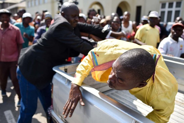 A man accused of supporting Zimbabwe President is thrown into the back of a pick up truck on November 21, 2017 outside parliament, as Parliament prepares to start impeachment proceedings against the President, while ousted vice president who could be the country's next leader, tells him to step down. As the 93-year-old autocrat faced intensifying pressure to quit, southern Africa's regional bloc announced it was dispatching the presidents of Angola and South Africa to Harare to discuss the crisis. / AFP PHOTO / TONY KARUMBA