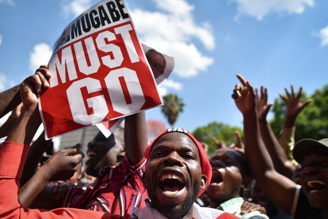 An anti-Zimbabwe President holds a placard during a gathering at Unity square, on November 21, 2017 in the capital Harare, praying and asking for Mugabe's impeachment, as Parliament prepares to start impeachment proceedings against the President, while ousted vice president who could be the country's next leader, tells him to step down. As the 93-year-old autocrat faced intensifying pressure to quit, southern Africa's regional bloc announced it was dispatching the presidents of Angola and South Africa to Harare to discuss the crisis. / AFP PHOTO / TONY KARUMBA