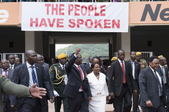 El presidente electo Emmerson Mnangagwa (C, L) gesticula mientras llega con su esposa Auxilia (C, R) en el Estadio Nacional Deportivo en Harare, el 24 de noviembre de 2017 durante la ceremonia de inauguración. El vicepresidente expulsado de Zimbabue prestaría juramento como presidente el 24 de noviembre de 2017, marcando el capítulo final de un drama político que derrocó a su predecesor después de una toma militar. / AFP PHOTO / Marco Longari