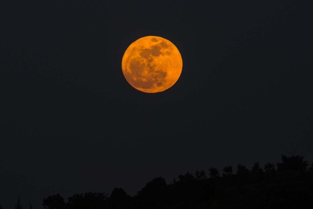 The supermoon rises over a highway near Yangon on December 3, 2017. The lunar phenomenon occurs when a full moon is at its closest point to earth. / AFP PHOTO / Ye Aung THU