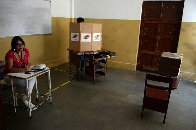 A woman sits next to a ballot box in a polling station during Venezuela's municipal elections, in San Cristobal, Tachira state, on December 10, 2017. / AFP PHOTO / GEORGE CASTELLANOS