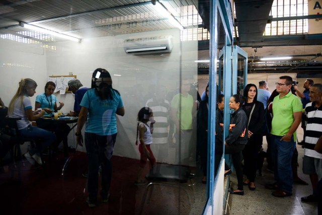 People queue outside the BanPanal communal bank to exchange bolivares for the new local community currency, the panal, launched in the "23 de Enero" working-class neighbourhood in Caracas on December 15, 2017. A collective in a hilltop shantytown in Caracas created its own currency, the panal, in an attempt to fight chronic shortages of cash in inflation-ridden Venezuela. The currency can be exchanged locally for staples like sugar, rice (produced in the neighborhood itself), and bread. / AFP PHOTO / FEDERICO PARRA