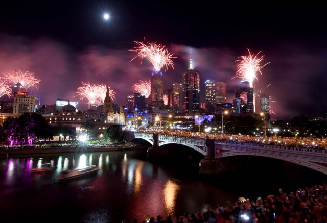 Fireworks light up the sky from building rooftops along the Yarra River during New Year's Eve celebrations in Melbourne early on January 1, 2018. / AFP PHOTO / Mal Fairclough