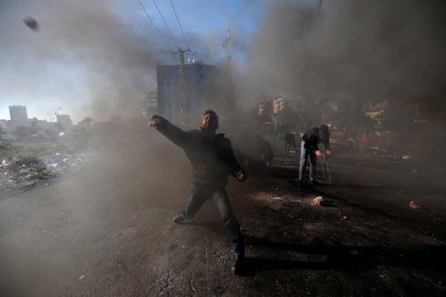 A Palestinian protester hurls stones towards Israeli troops during clashes as Palestinians call for a "day of rage" in response to U.S. President Donald Trump's recognition of Jerusalem as Israel's capital, near the Jewish settlement of Beit El, near the West Bank city of Ramallah December 8, 2017. REUTERS/Mohamad Torokman