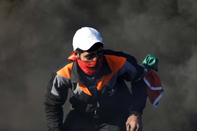 A Palestinian protester is seen as smoke rises from burning tires during clashes with Israeli troops as Palestinians call for a "day of rage" in response to U.S. President Donald Trump's recognition of Jerusalem as Israel's capital, near the Jewish settlement of Beit El, near the West Bank city of Ramallah December 8, 2017. REUTERS/Mohamad Torokman