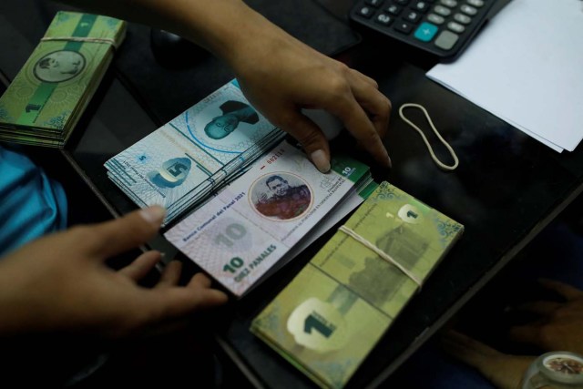 A cashier holds a stack of 10 Panal notes depicting Venezuela's late President Hugo Chavez at a branch of BanPanal communal bank in Caracas, Venezuela December 15, 2017. REUTERS/Marco Bello