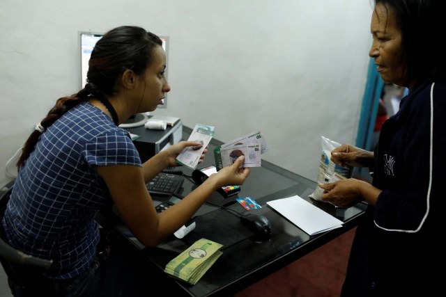 Una cajera explica el valor de cambio de un billete de panel a una mujer en una sucursal del banco comunal BanPanal en Caracas, Venezuela, 15 de diciembre de 2017. REUTERS/Marco Bello