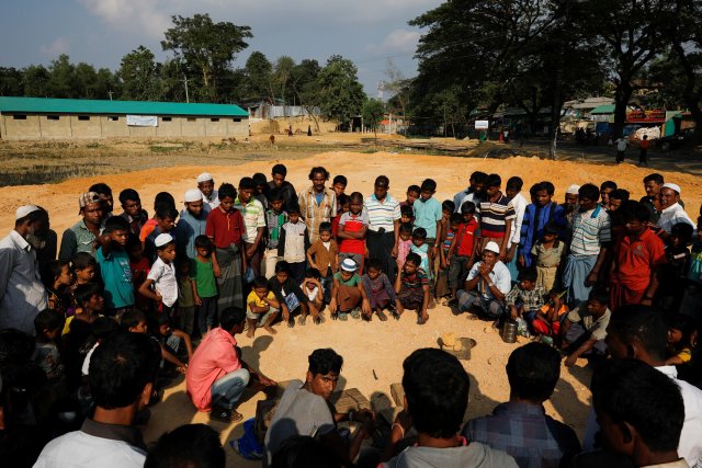 Rohingya refugees gather to see a man performing with a snake at the Kutupalong refugee camp near Cox's Bazar, Bangladesh December 21, 2017. REUTERS/Marko Djurica