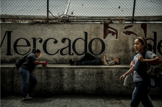 Un anciano tomó una siesta bajo una representación en Caracas de la atenta mirada del ex presidente Hugo Chávez. El líder de toda la vida fue amado y odiado con casi el mismo fervor. Foto: Meridith Kohut para The New York Times