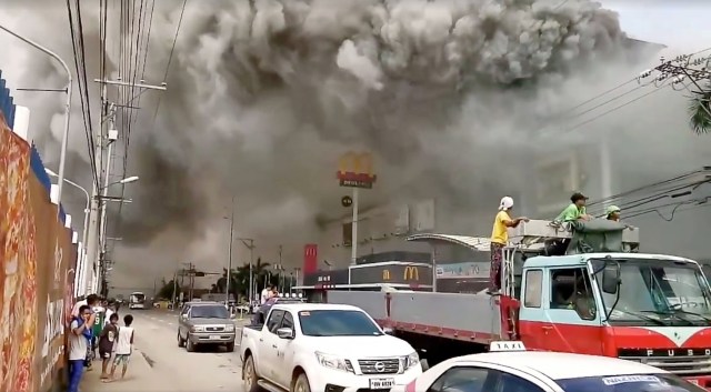 People watch as smoke rises from burning mall's 3rd floor, in Davao City, Philippines, in this December 23, 2017 picture obtained from social media. Courtesy Otto van Dacula via REUTERS THIS IMAGE HAS BEEN SUPPLIED BY A THIRD PARTY. MANDATORY CREDIT. NO RESALES. NO ARCHIVES