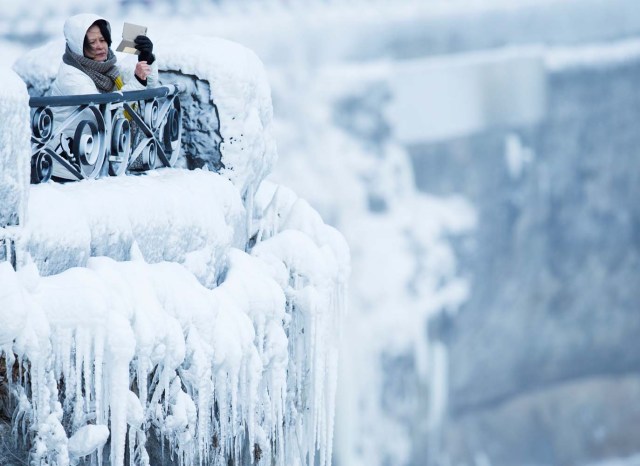 A visitor takes pictures near the brink of the ice covered Horseshoe Falls in Niagara Falls, Ontario, Canada, January 3, 2018. REUTERS/Aaron Lynett