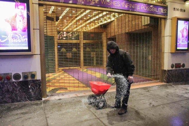 A worker dumps road salt during a snowstorm in Times Square in Manhattan, in New York, U.S., January 4, 2018. REUTERS/Jeenah Moon