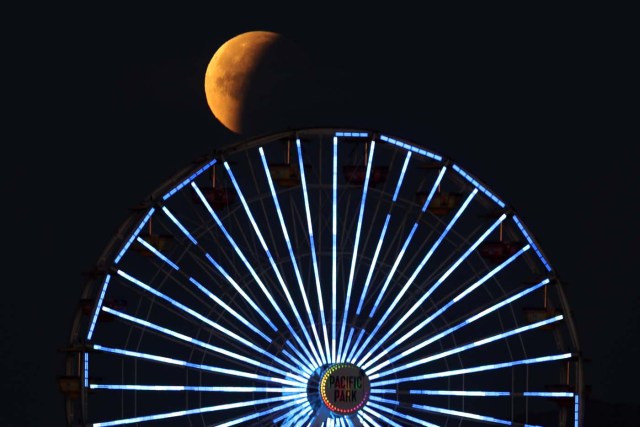 A lunar eclipse of a full "Blue Moon" is seen above the ferris wheel on the Santa Monica Pier in Santa Monica, California, U.S., January 31, 2018. REUTERS/Lucy Nicholson