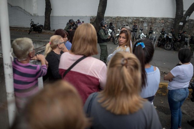 CAR09. CARACAS (VENEZUELA), 17/01/2018.- Varias mujeres observan a miembros de la Guardia Nacional Bolivariana y la Policía Nacional Bolivariana que custodian las inmediaciones de la morgue en donde está cuerpo del exagente Pérez hoy, miércoles 17 de enero de 2018, en Caracas (Venezuela). Decenas de agentes de la Policía Nacional Bolivariana custodian desde la mañana de hoy los alrededores de la principal morgue de Caracas, después de que familiares de Óscar Pérez, el exagente alzado contra el Gobierno chavista quien falleció el lunes, exigieran identificar su cuerpo. EFE/MIGUEL GUTIÉRREZ