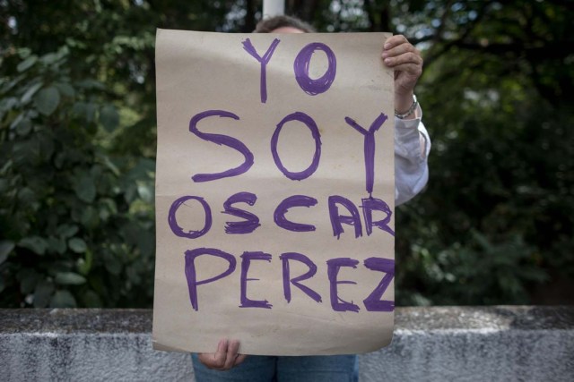 CAR10. CARACAS (VENEZUELA), 17/01/2018.- Una mujer sostiene un cartel en el que se lee "Yo soy Óscar Pérez" frente a miembros de la Guardia Nacional Bolivariana y la Policía Nacional Bolivariana que custodian las inmediaciones de la morgue en donde está cuerpo del exagente Pérez hoy, miércoles 17 de enero de 2018, en Caracas (Venezuela). Decenas de agentes de la Policía Nacional Bolivariana custodian desde la mañana de hoy los alrededores de la principal morgue de Caracas, después de que familiares de Óscar Pérez, el exagente alzado contra el Gobierno chavista quien falleció el lunes, exigieran identificar su cuerpo. EFE/MIGUEL GUTIÉRREZ