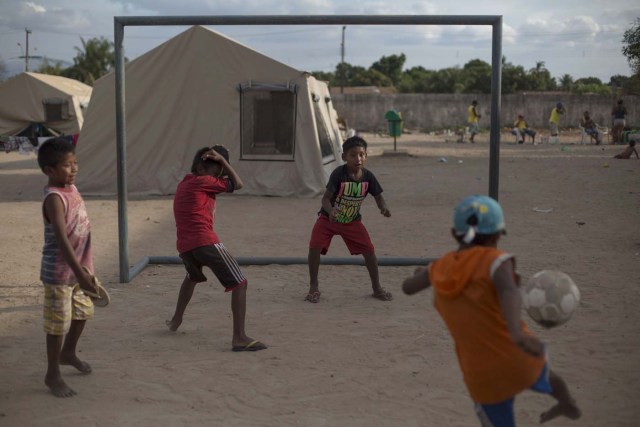 Children from the Venezuelan indigenous tribe Warao play football at a shelter in the city of Boa Vista, Roraima, Brazil, on February 24, 2018. According with local authorities, around one thousand refugees are crossing the Brazilian border each day from Venezuela. With the constant influx of Venezuelan immigrants most are living in shelters and the streets of Boa Vista and Paracaima cities. / AFP PHOTO / MAURO PIMENTEL