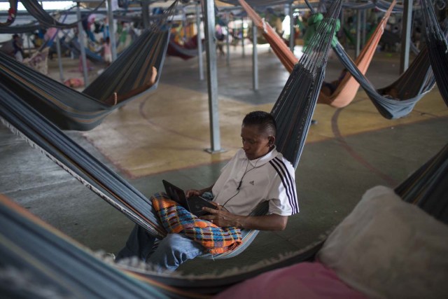 Venezuelan refugee indigenous watches a movie inside a shelter in the city of Boa Vista, Roraima, Brazil, on February 24, 2018. According with local authorities, around one thousand refugees are crossing the Brazilian border each day from Venezuela. With the constant influx of Venezuelan immigrants most are living in shelters and the streets of Boa Vista and Paracaima cities, looking for work, medical care and food. Most are legalizing their status to stay and live in Brazil. / AFP PHOTO / MAURO PIMENTEL