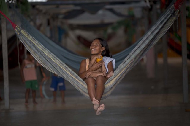 A Venezuelan indigenous refugee gives water to her daughter inside a shelter in the city of Boa Vista, Roraima, Brazil, on February 24, 2018. According with local authorities, around one thousand refugees are crossing the Brazilian border each day from Venezuela. With the constant influx of Venezuelan immigrants most are living in shelters and the streets of Boa Vista and Paracaima cities, looking for work, medical care and food. Most are legalizing their status to stay and live in Brazil. / AFP PHOTO / MAURO PIMENTEL