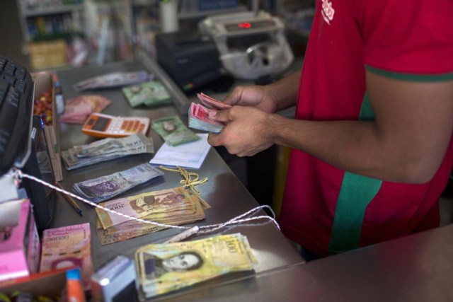 A Brazilian shopkeeper counts Venezuelan money received from Venezuelans crossing the border to buy food at Pacaraima, Roraima, Brazil, on February 27, 2018. According to local authorities, around one thousand refugees are crossing the Brazilian border each day from Venezuela. With the constant influx of Venezuelan immigrants, most are living in shelters and the streets of Boa Vista and Pacaraima cities, looking for work, medical care and food. Most are legalizing their status to stay and live in Brazil. / AFP PHOTO / Mauro Pimentel / TO GO WITH AFP STORY by Paula RAMÓN
