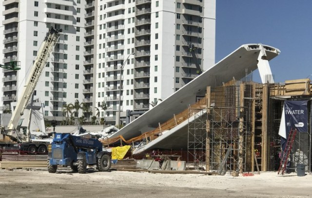 Se ve una grúa cerca de un puente peatonal recién instalado, que colapsó, sobre una carretera de seis carriles en Miami, Florida, el 15 de marzo de 2018, aplastando a varios autos y, según informes, dejando varias personas muertas. The Miami Herald informó que un número desconocido de personas quedaron atrapadas debajo de la pasarela colapsada, que conectaba a la Universidad Internacional de Florida con un área de viviendas estudiantiles y fue erigida hace menos de una semana. / AFP PHOTO / AFP TV / Antoni BELCHI