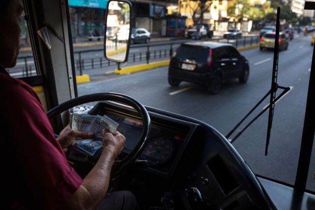 Un conductor de autobús cuenta los bolívares en Caracas. Fotógrafo: Wil Riera / Bloomberg