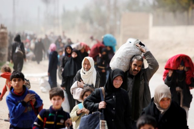 Personas caminan con sus pertenencias huyendo de la ciudad de Hammouriyeh, controlada por los rebeldes, en la aldea de Beit Sawa, al este de Guta, Siria, el 15 de marzo de 2018. REUTERS / Omar Sanadiki