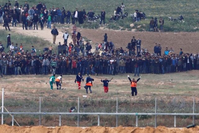 Palestinian paramedics evacuate an injured man on the Gaza side of the Israel-Gaza border, as seen from the Israeli side of the border, March 30, 2018. REUTERS/Amir Cohen