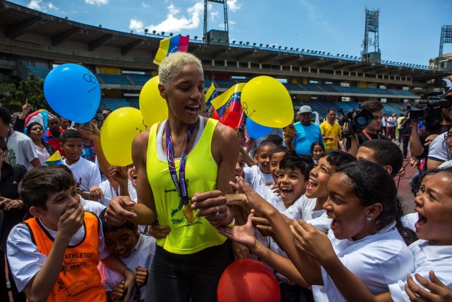 CAR01. CARACAS, 08/03/2018.- La atleta de triple salto venezolana Yulimar Rojas (c) saluda a un grupo de niños hoy, jueves 8 de marzo de 2018, durante un encuentro con la prensa después de ganar el campeonato mundial de triple salto bajo techo, en Caracas (Venezuela). La bicampeona mundial de triple salto, la venezolana Yulimar Rojas, felicitó hoy a su rival y compañera de entrenamiento, Ana Peleteiro, de quien dijo "encontró la luz" con su desempeño en el último campeonato mundial de atletismo, en el que la española se alzó con un histórico bronce. EFE/CRISTIAN HERNÁNDEZ